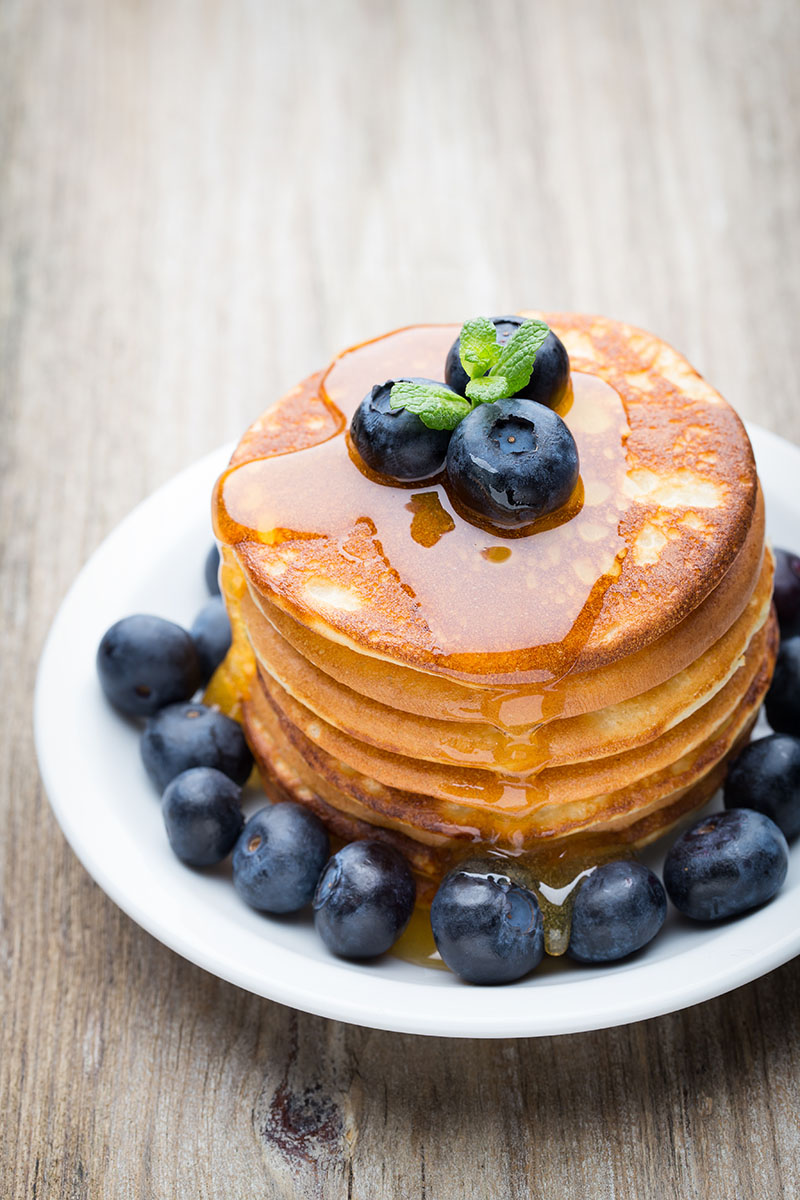 Stack of pancakes with blueberries and maple syrup